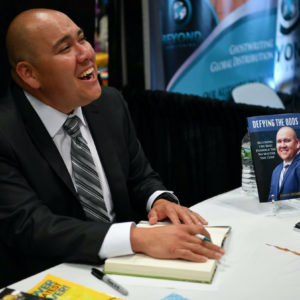 Author James Merrifiled sings copies of DEFYING THE ODDS at Book Expo in NYC with Beyond Publishing
