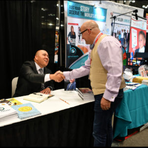 Author James Merrifiled sings copies of DEFYING THE ODDS at Book Expo in NYC with Beyond Publishing